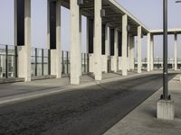 a parking lot with columns and a walkway between two building fronts that span the sky