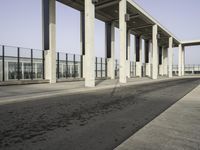 a parking lot with columns and a walkway between two building fronts that span the sky