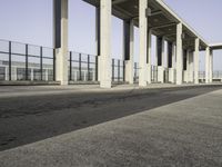 a parking lot with columns and a walkway between two building fronts that span the sky