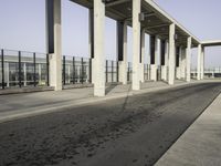 a parking lot with columns and a walkway between two building fronts that span the sky
