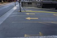 two yellow arrows pointing left into an underground parking lot in the city side street,