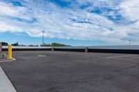 a parking lot with many storage containers under a cloudy blue sky by the docks area