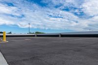 a parking lot with many storage containers under a cloudy blue sky by the docks area