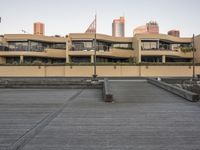 an empty parking lot with benches and a sidewalk in front of the buildings near the road