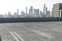 a woman standing in a parking lot with buildings in the background with her suitcase behind her