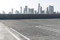 a woman standing in a parking lot with buildings in the background with her suitcase behind her