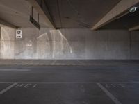 parking spaces with parking permit sign in city parking lot area under bridge - side structure