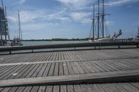 the pier in the harbor with two sailboats and benches for seating on the water
