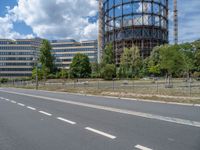 there is an empty street in front of a huge building under construction with trees around