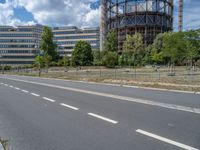 there is an empty street in front of a huge building under construction with trees around