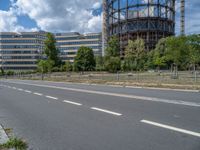 there is an empty street in front of a huge building under construction with trees around