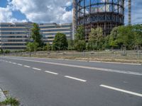 there is an empty street in front of a huge building under construction with trees around