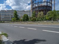 there is an empty street in front of a huge building under construction with trees around