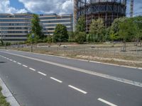 there is an empty street in front of a huge building under construction with trees around