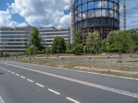 there is an empty street in front of a huge building under construction with trees around