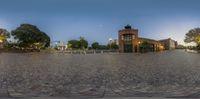 a picture of some buildings in a circle on a paved area with trees and lights