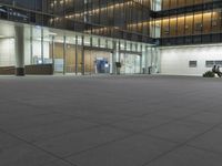 a concrete plaza at night with a metal railing and a building in the background at night
