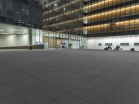 a concrete plaza at night with a metal railing and a building in the background at night