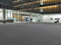 a concrete plaza at night with a metal railing and a building in the background at night
