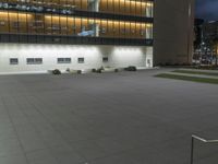 a concrete plaza at night with a metal railing and a building in the background at night