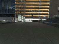 a concrete plaza at night with a metal railing and a building in the background at night