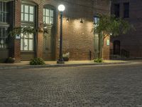 an empty parking lot at night with some planters in pots next to it and two lighted street lamps