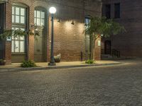 an empty parking lot at night with some planters in pots next to it and two lighted street lamps