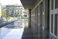the reflection of the city buildings on the water floor in a walkway next to an open building