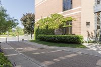 a large brick building sitting next to a lush green tree filled area of grass,