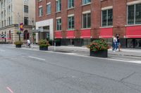 a street with tall buildings along it and flowers growing in containers next to the curb