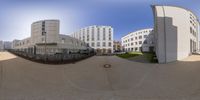 360 lens photo of large buildings around a street in the city with a fountain on the sidewalk