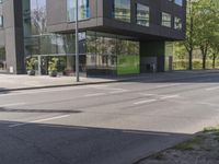 this is a bus stop on the street that is next to the building and some trees