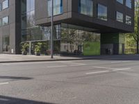 this is a bus stop on the street that is next to the building and some trees