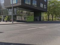 this is a bus stop on the street that is next to the building and some trees