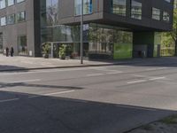 this is a bus stop on the street that is next to the building and some trees