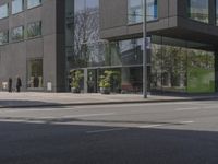 this is a bus stop on the street that is next to the building and some trees