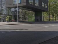 this is a bus stop on the street that is next to the building and some trees