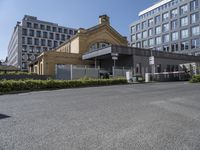 the building is surrounded by two very large buildings on the other side of the road