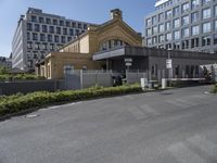 the building is surrounded by two very large buildings on the other side of the road