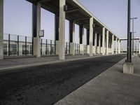 street by a concrete structure with pillars and lamps on it, leading to the train station