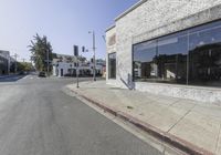 an empty city street and a building on the corner in front of it on a sunny day