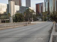 an empty street with cars on it, next to a city skyline and tall buildings