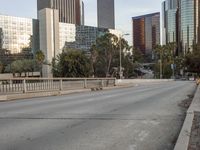 an empty street with cars on it, next to a city skyline and tall buildings