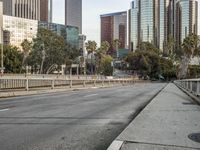 an empty street with cars on it, next to a city skyline and tall buildings