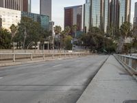 an empty street with cars on it, next to a city skyline and tall buildings