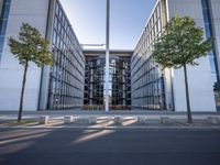 the office building is next to the trees near the sidewalk and walkways with trees