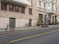 several bikes that are parked on the side of the road next to some buildings with windows