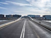 a road with a bridge that extends it over a city area, with many buildings on the side