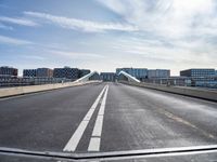 a road with a bridge that extends it over a city area, with many buildings on the side