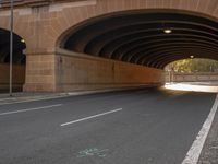 an empty street in the middle of an old stone tunnel overpass that goes across a small road